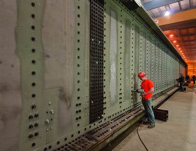 Railroad Bridge Worker drilling bolt holes in a fabricated railroad bridge at a Greiner facility
