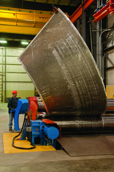 Cones Worker operating a rolling and forming machine to create an aluminum cone at a Greiner facility